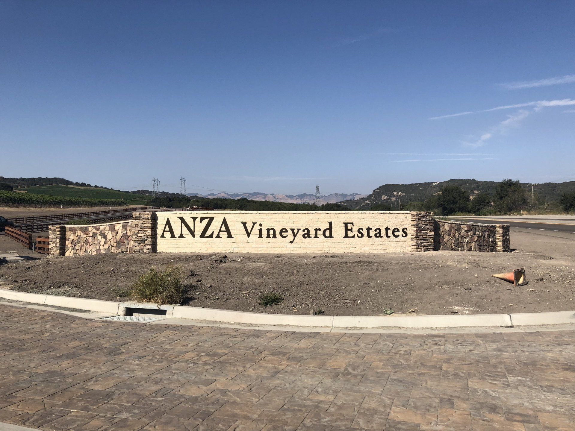 ANZA Vineyard Estates entrance sign on a stone wall under a clear blue sky