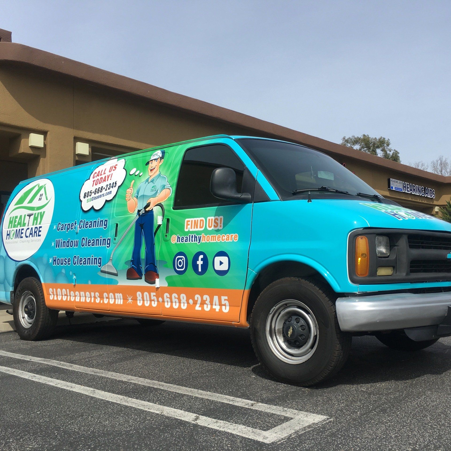 Bright turquoise-and-orange service van with cleaning company branding parked in a lot