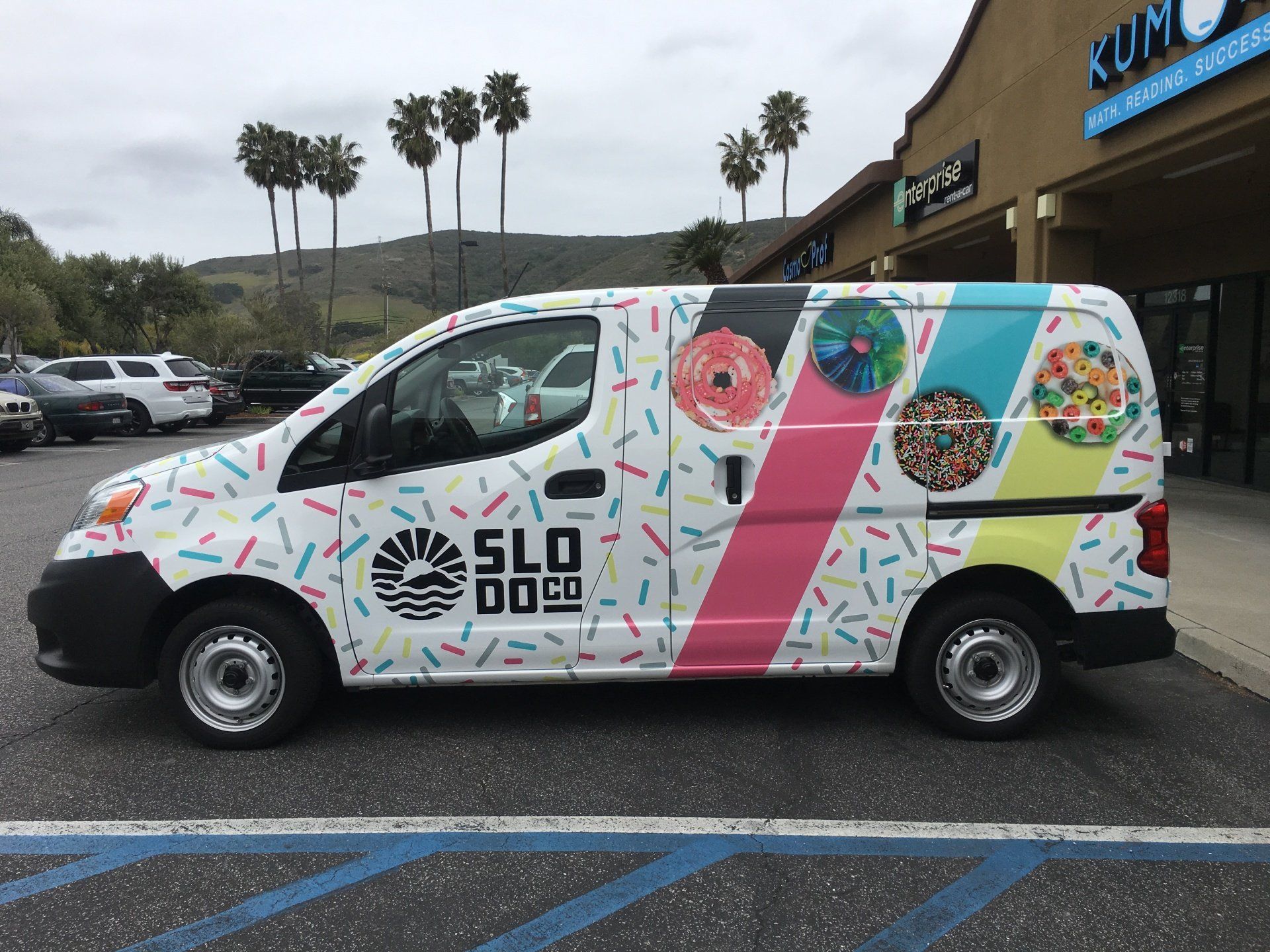 Colorful branded van parked outside a storefront on a cloudy day