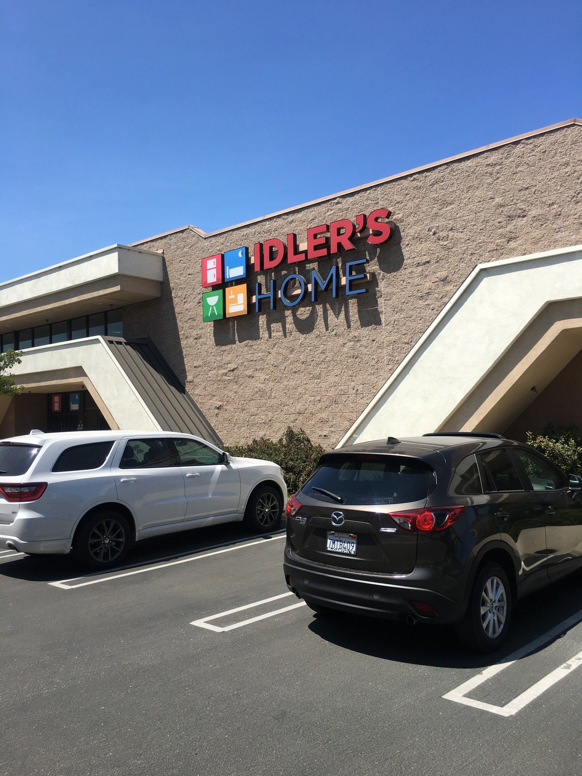 Idler’s Home store exterior with parked SUVs under a bright blue sky