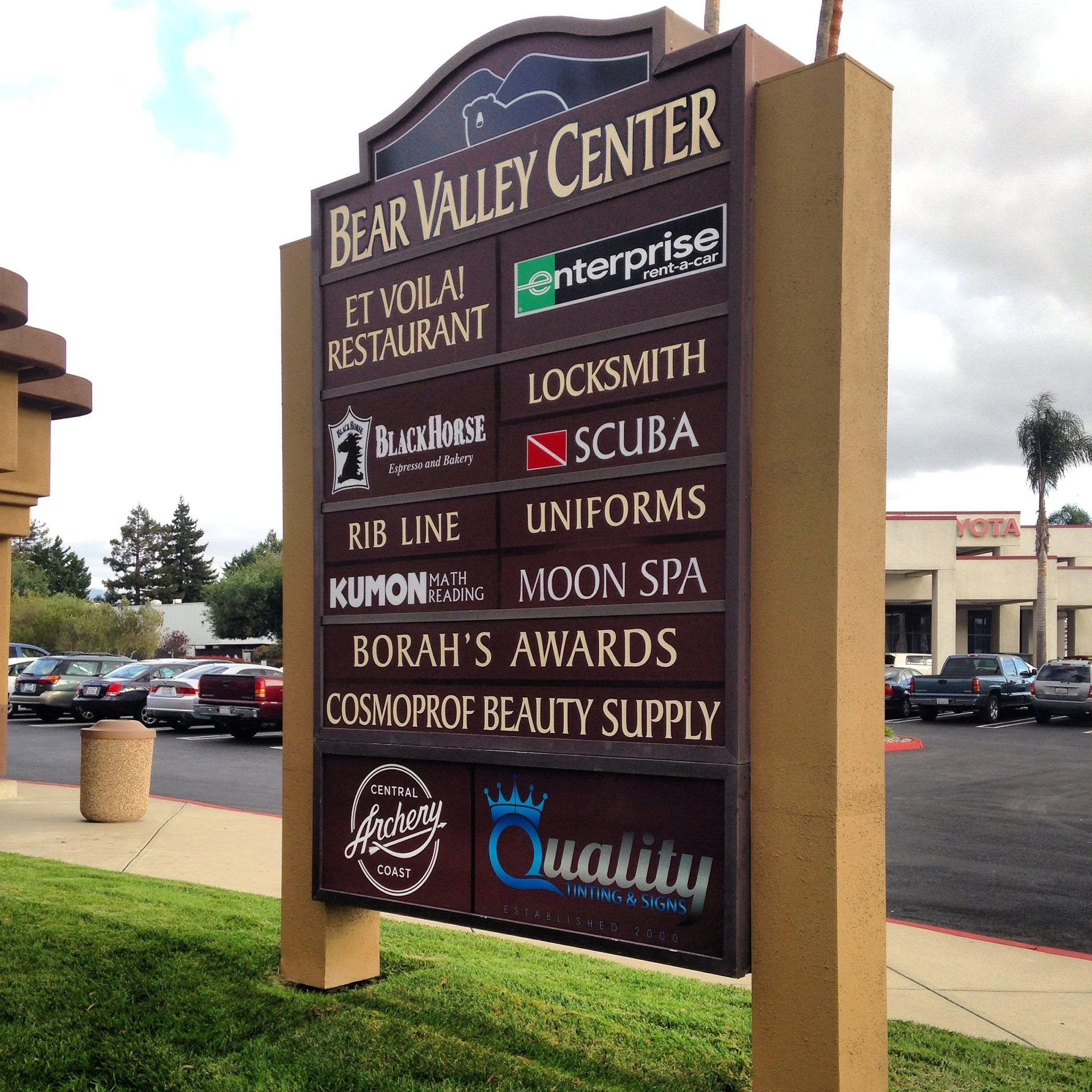 Bear Valley Center shopping plaza sign with tenant listings in a parking lot