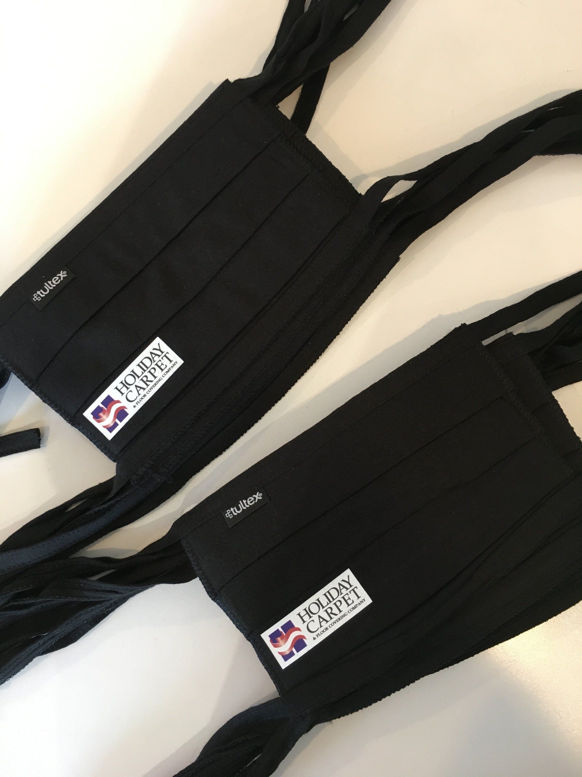 Two black corset-style tops with laced straps and small label patches on a light background