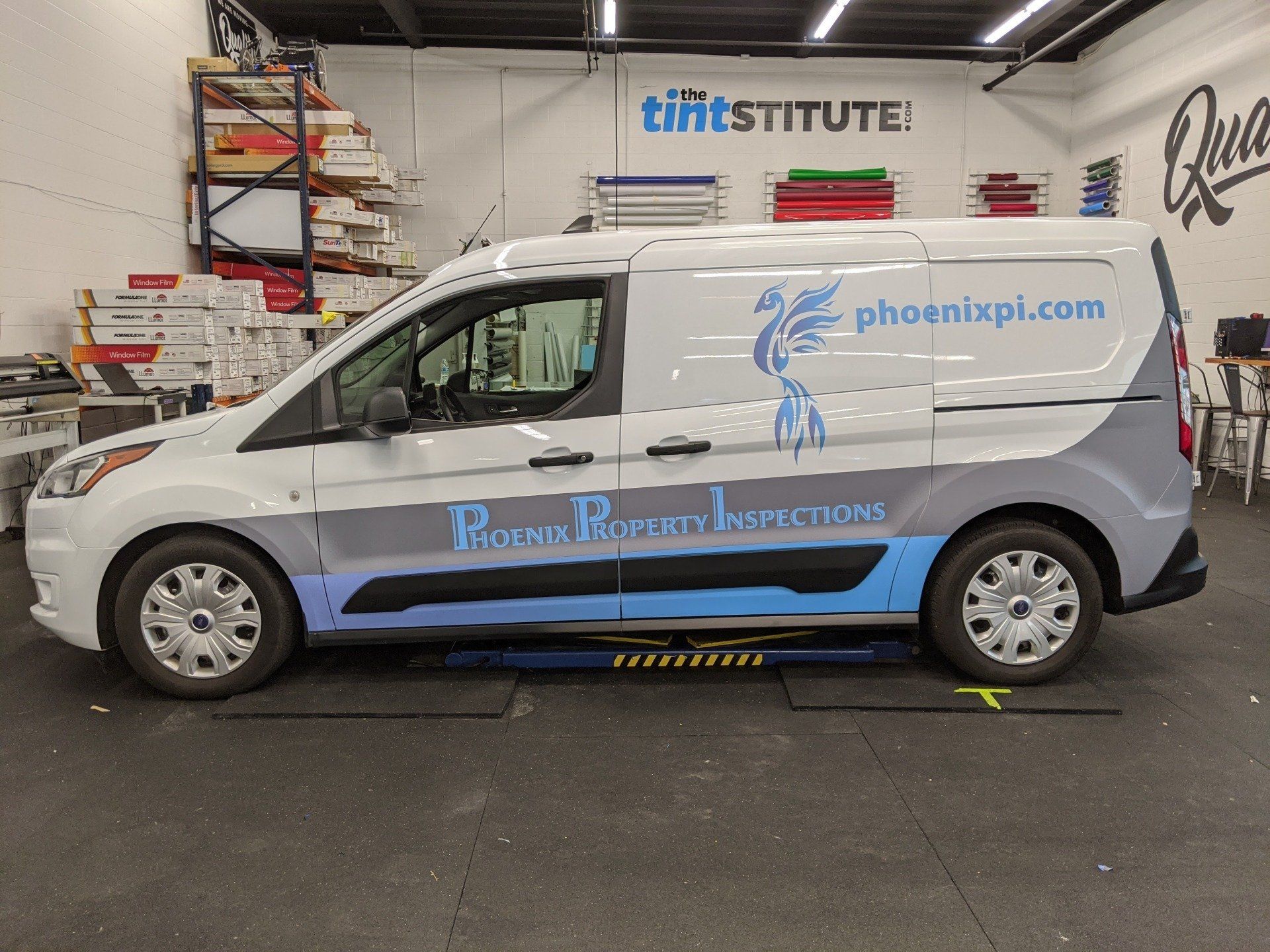 White inspection van parked indoors with blue branding and website text on the side