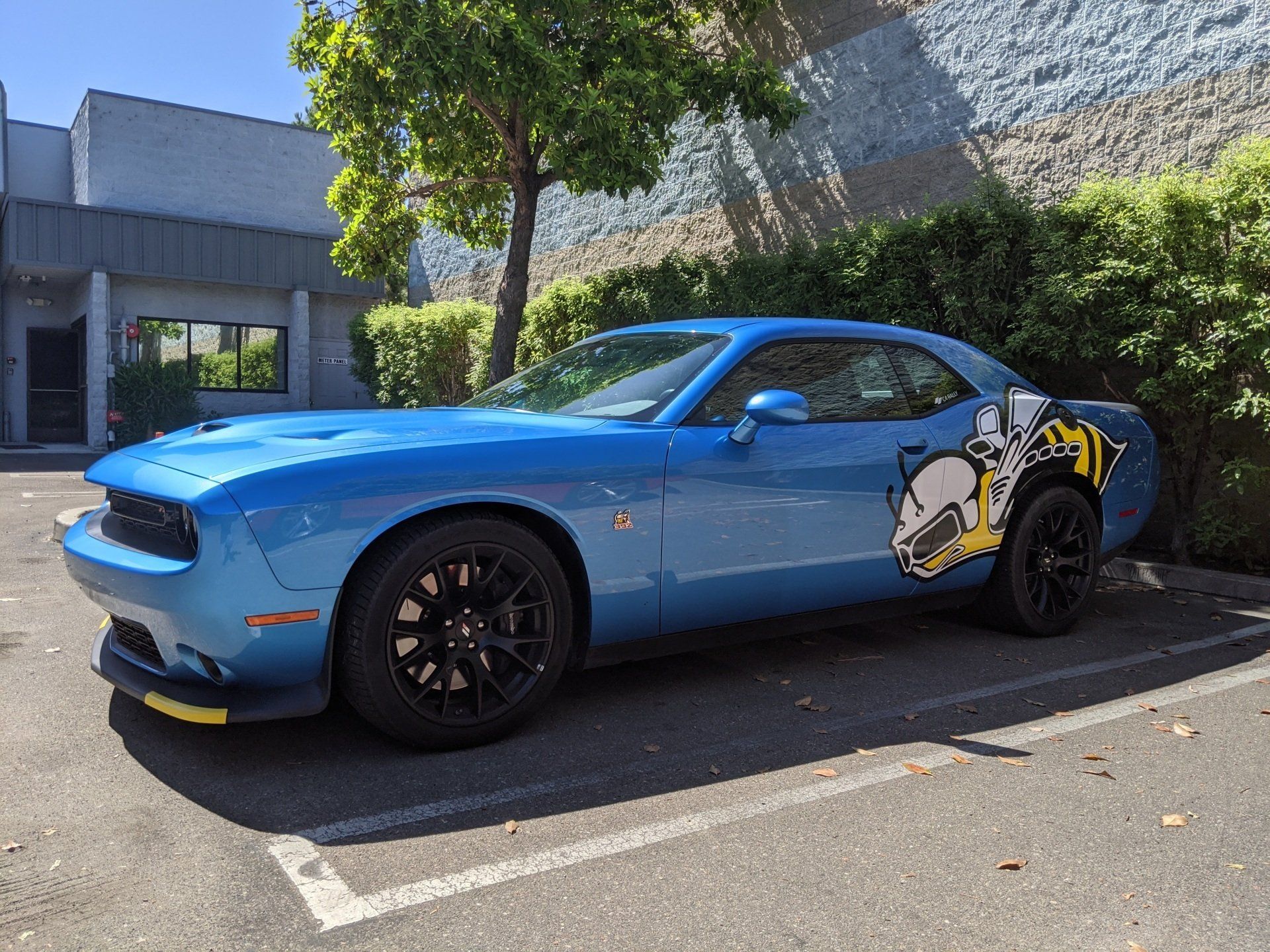 Blue Dodge Challenger parked on a street, with a large cartoon character decal on the side.