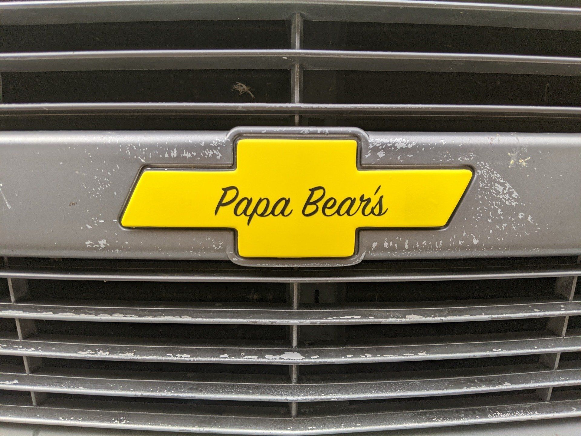 Yellow “Papa Bear’s” sign on a car grille with horizontal black slats.