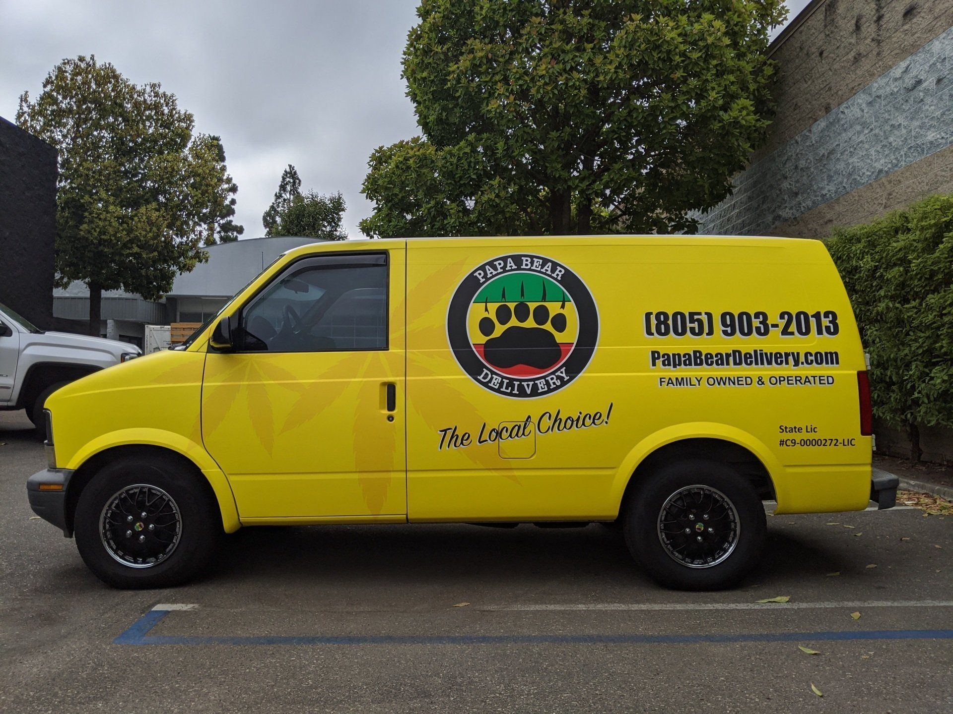 Yellow service van with black paw logo and phone number parked outdoors in a lot