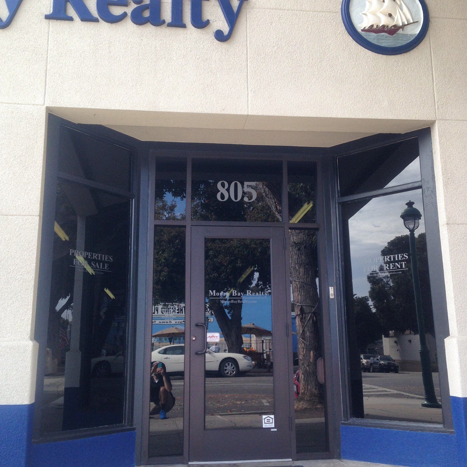 Realty office entrance with glass doors, address 805, and blue awning accents