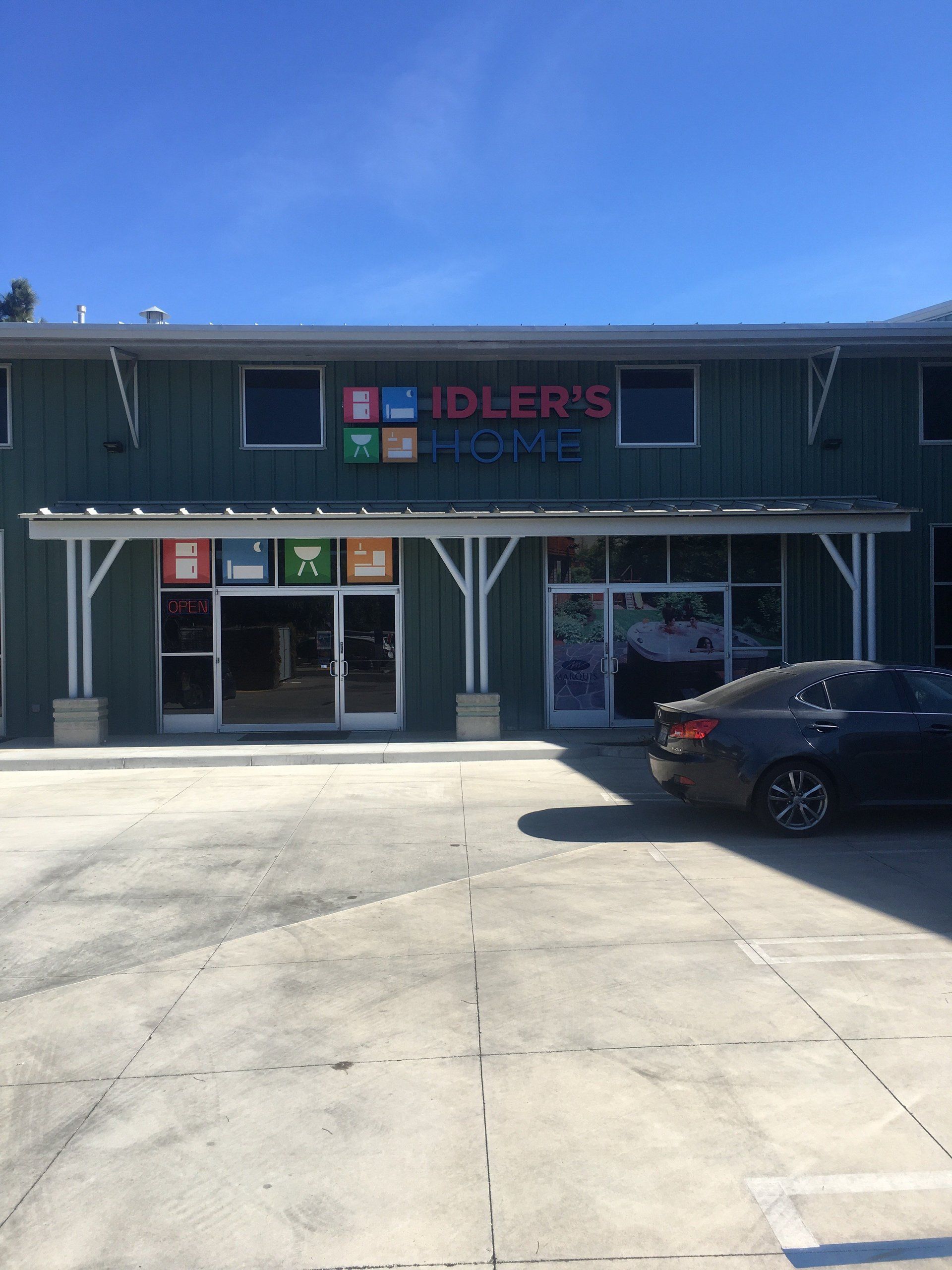 Storefront with “IDLER’S” sign, blue exterior, and a black car parked outside under a clear sky.