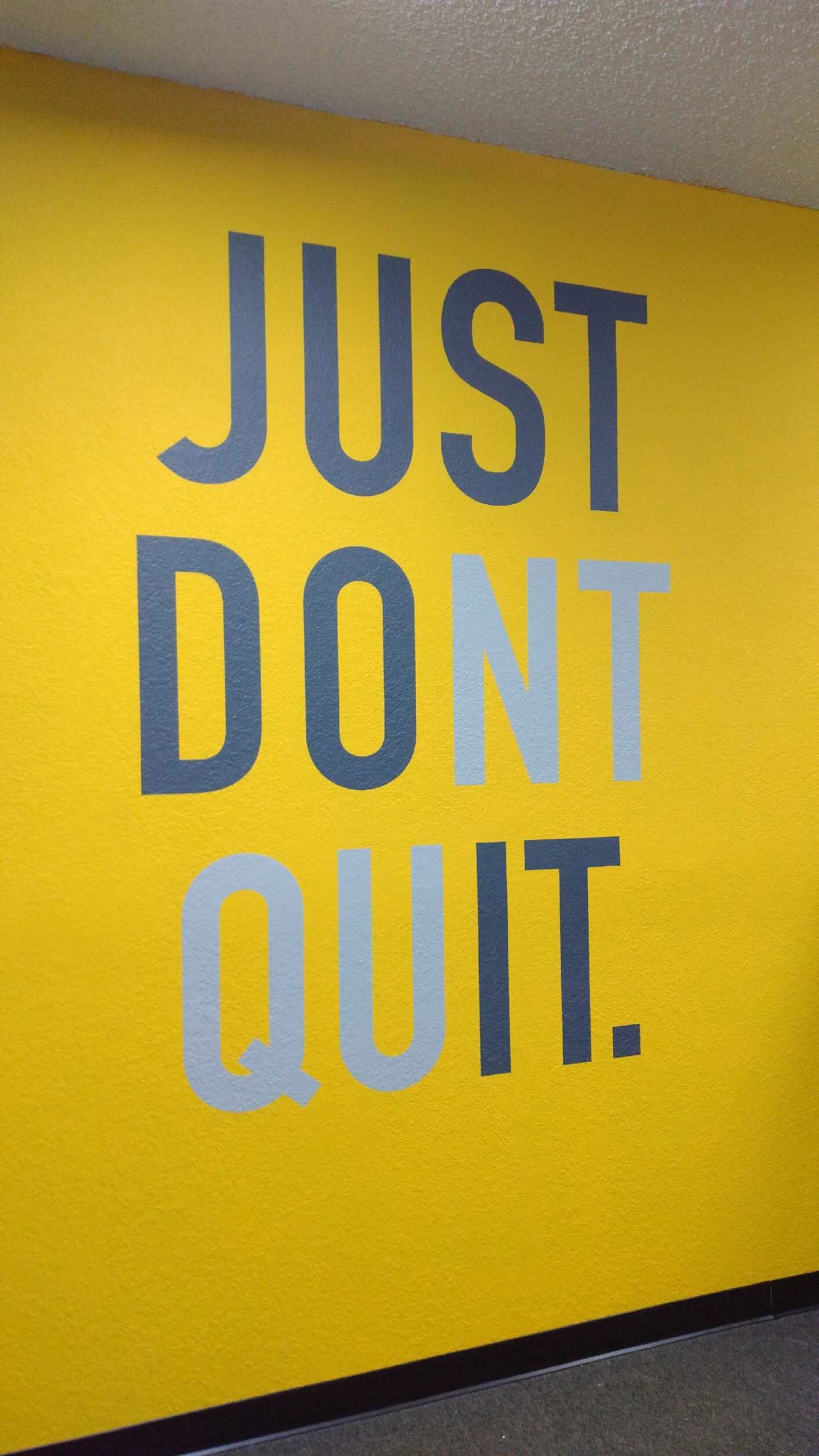 Yellow wall with blue “JUST DON’T QUIT.” motivational text