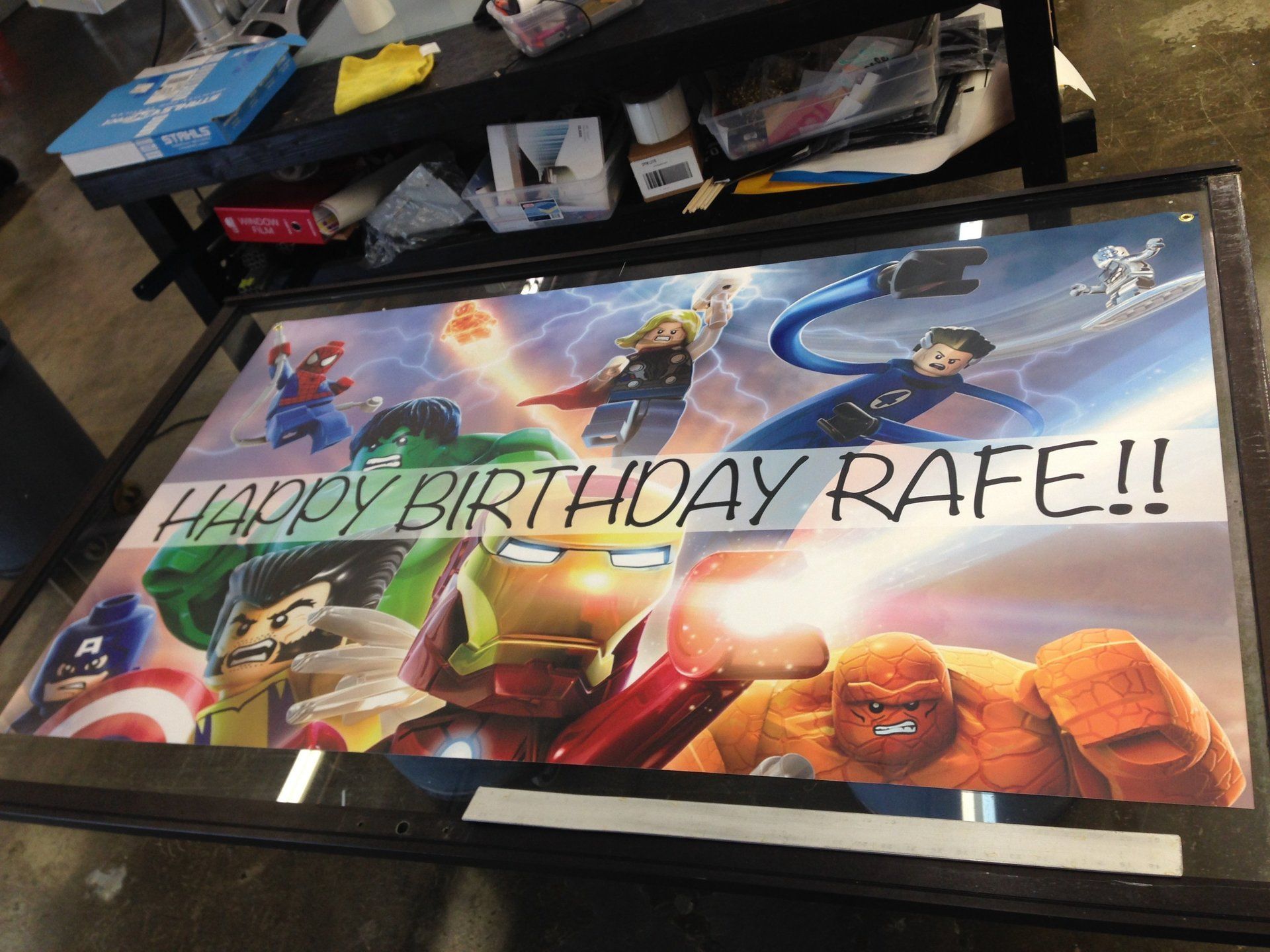 Comic-themed birthday poster on a table, with large text reading “HAPPY BIRTHDAY RAPE!!”