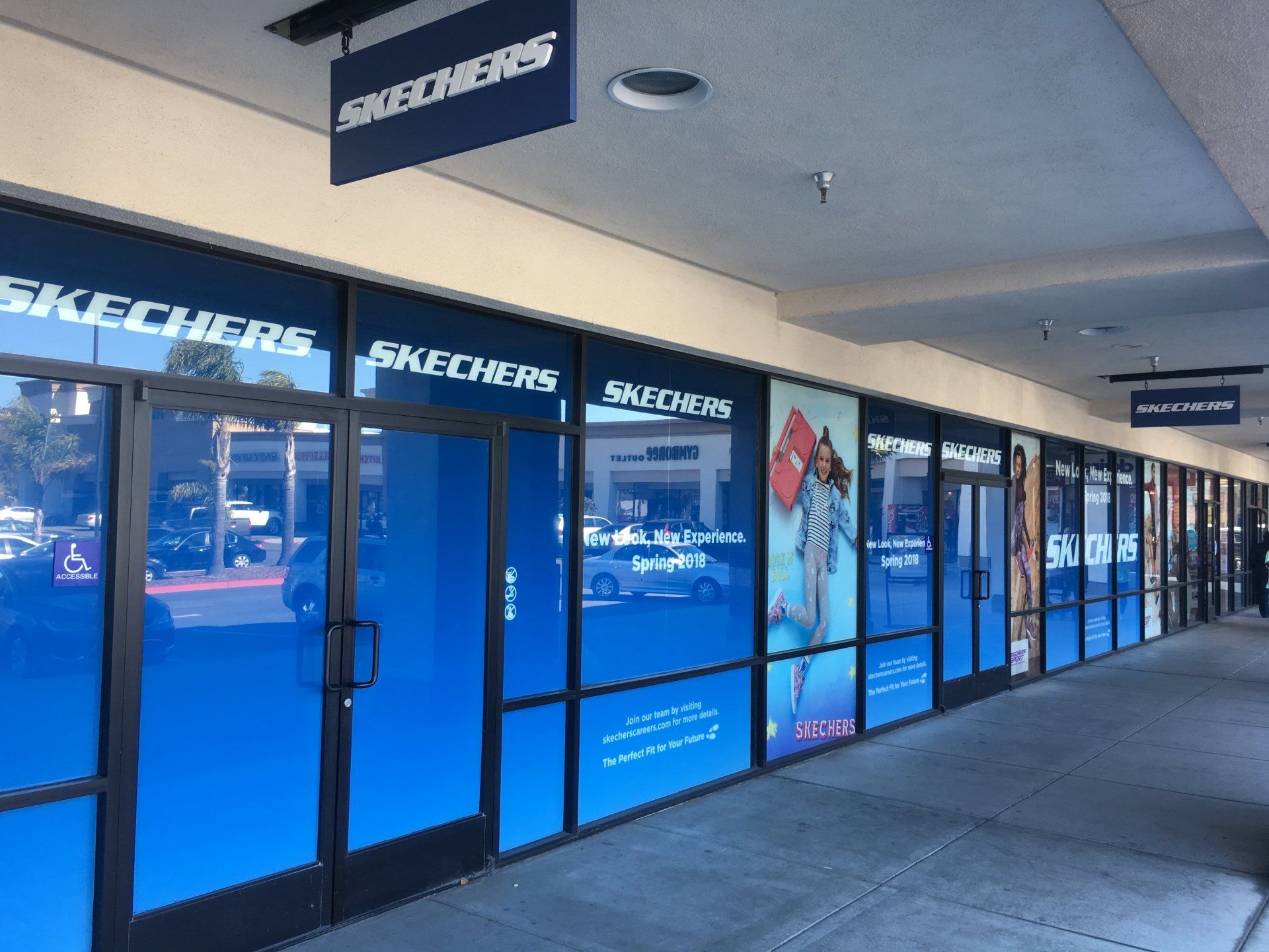 Skechers storefront with blue window graphics and sidewalk arcade in front