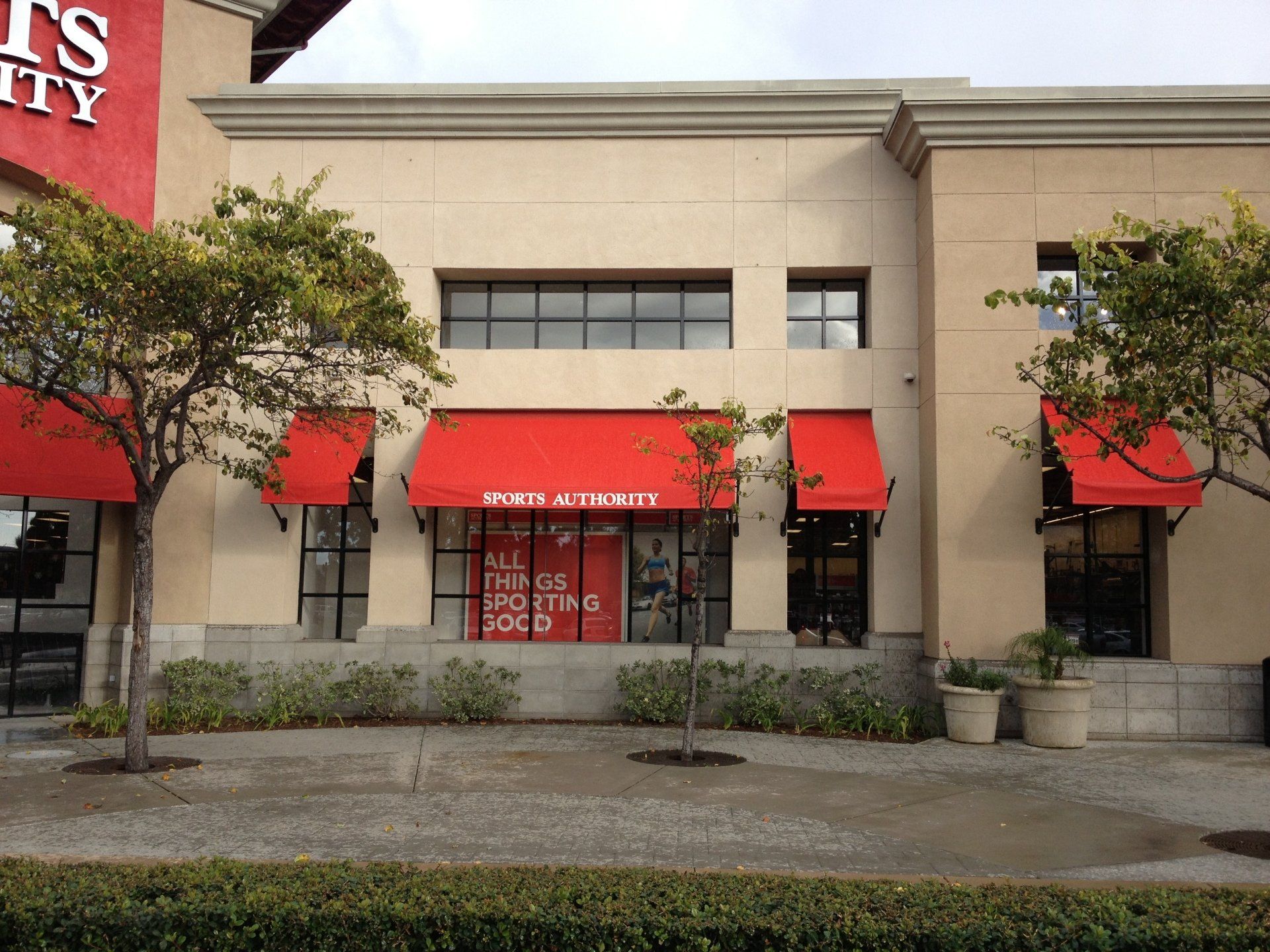 Storefront with red awnings and large windows in a shopping center.