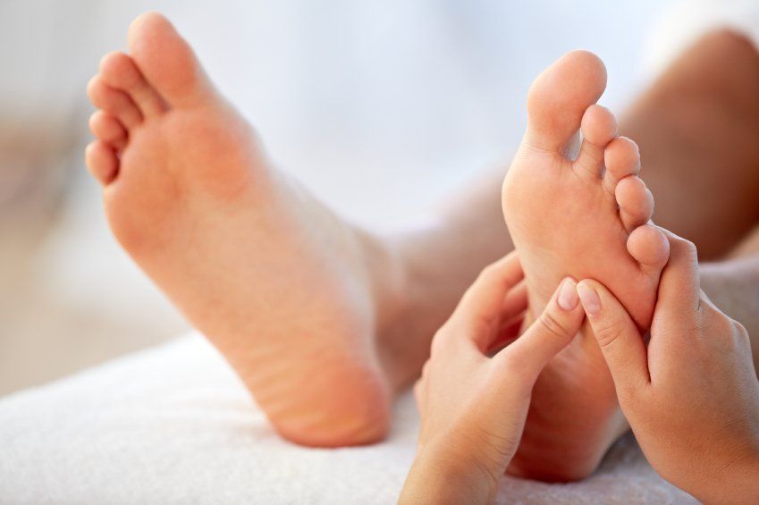 Mani che massaggiano la pianta del piede, concentrandosi sugli archi plantari.