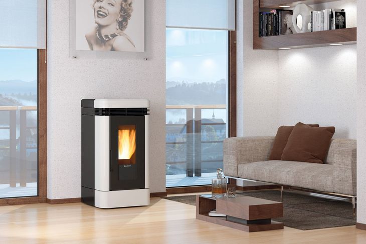 Soggiorno moderno con stufa a pellet accesa, divano, tavolino da caffè e ampie finestre con vista sull'acqua.