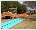 Bulldozer and Pipes — Bulldozer and Pipes used to Install Water Main in Shelby, NC Bulldozer and Pipes — Bulldozer and Pipes used to Install Water Main in Shelby, NC