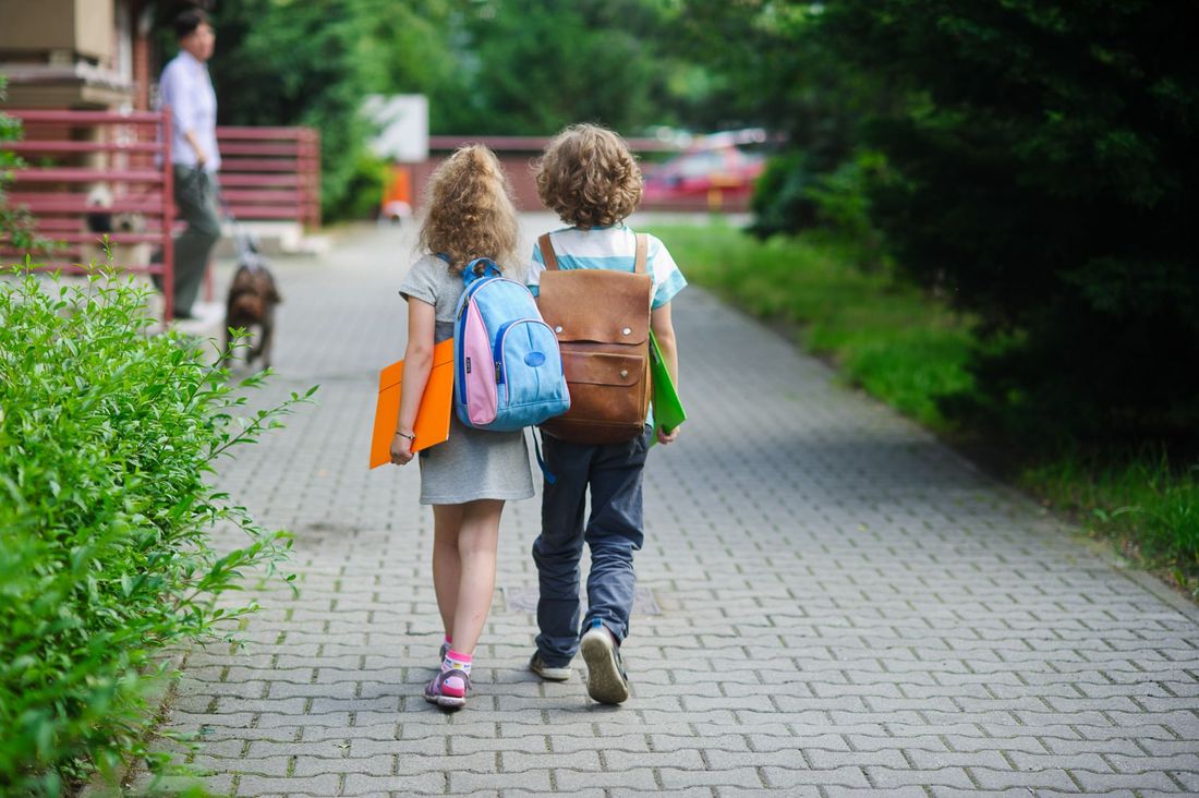 bambini con carpetta e zaino mentre entrano a scuola