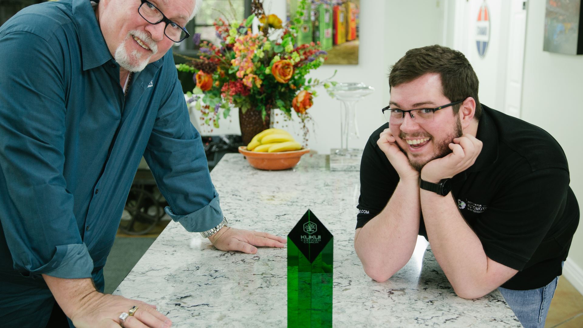 Two men are standing next to each other on a kitchen counter.