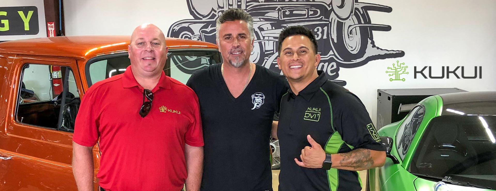 Three men are posing for a picture in front of a green car.