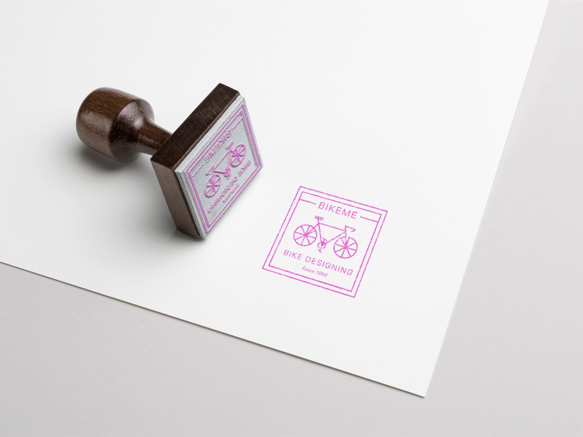 Rubber stamp imprinting a pink bicycle logo on white paper