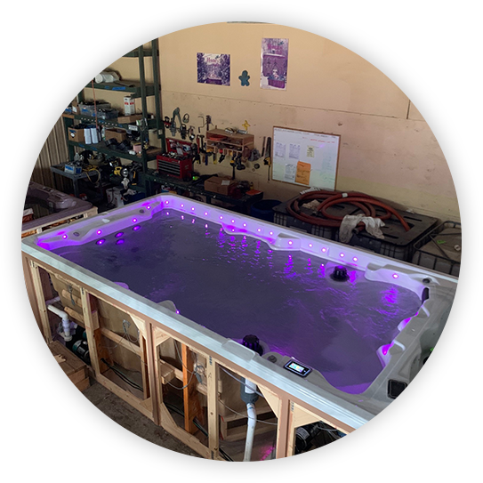A partially built swimming pool with purple lights in a workshop.