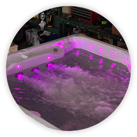 Hot tub with pink lights, bubbling water, in a workshop setting.