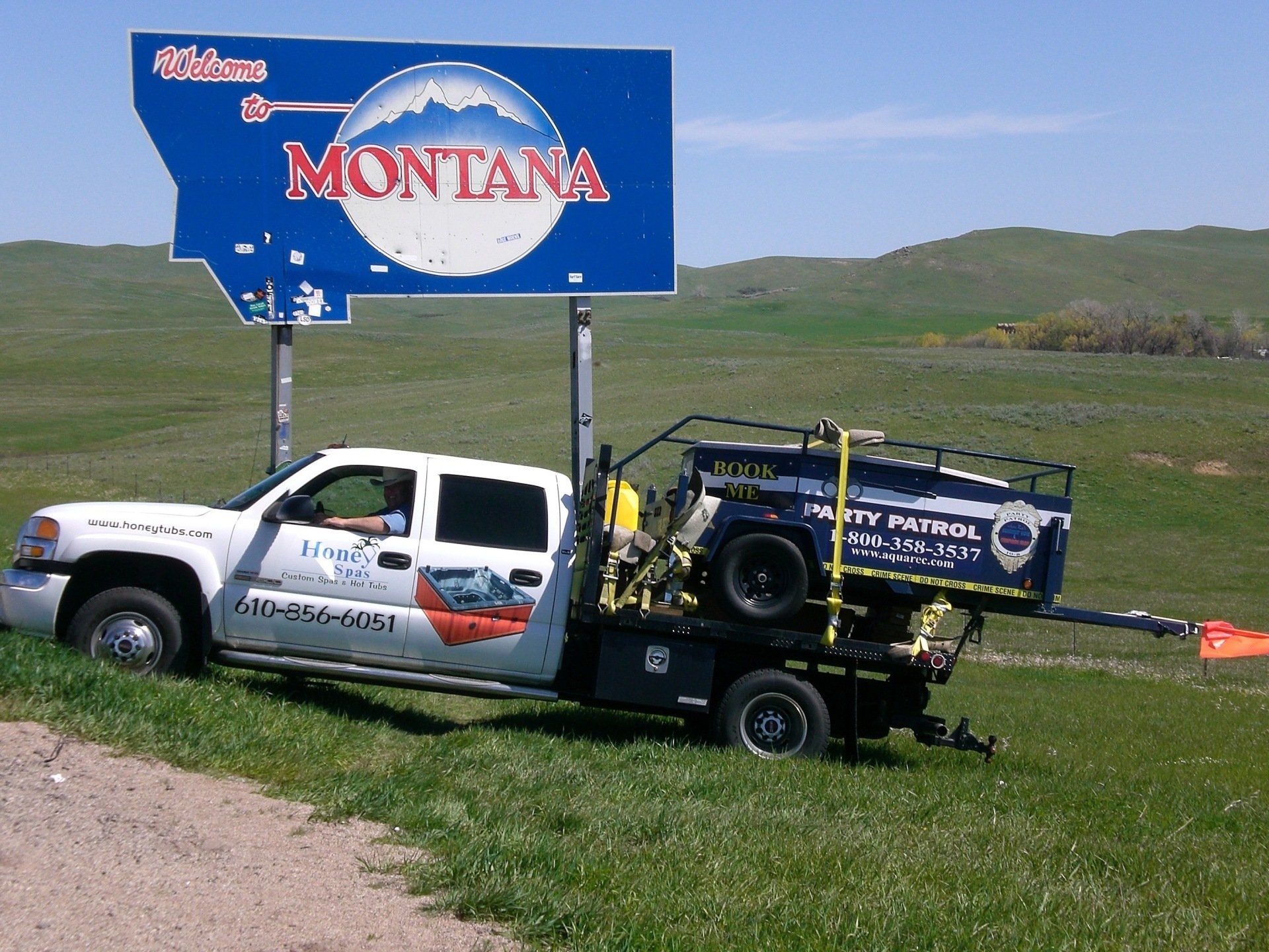 White truck with a trailer in Montana, under the state sign.