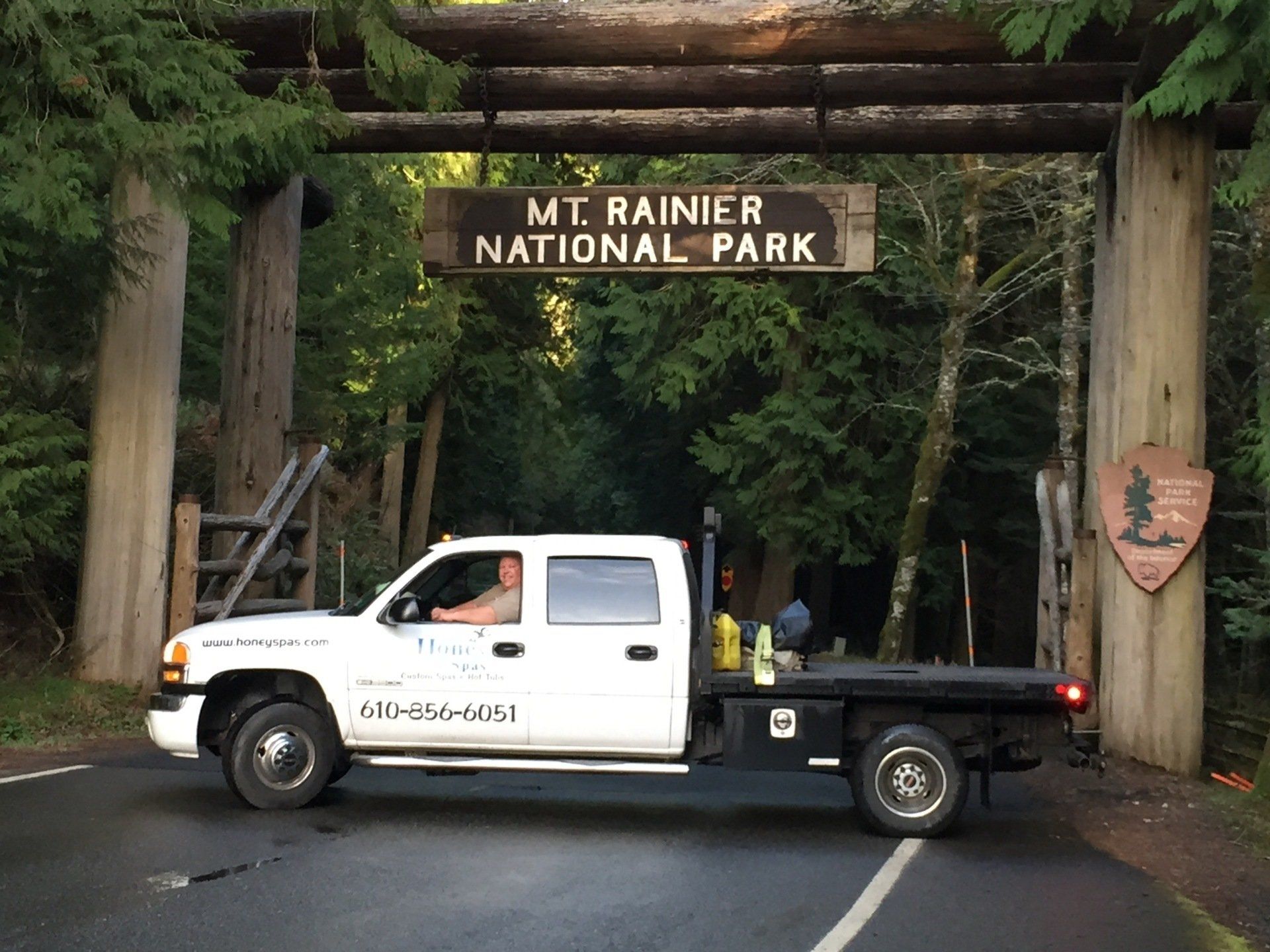 White truck passing under Mt. Rainier National Park archway.