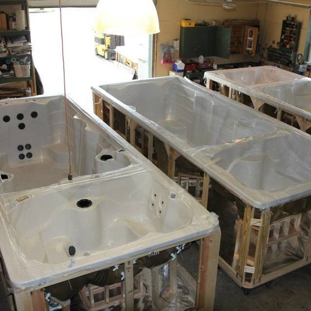 Three white rectangular tubs with wooden frames inside a workshop.