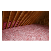 Attic with pink insulation batts beneath a slanted wooden roof