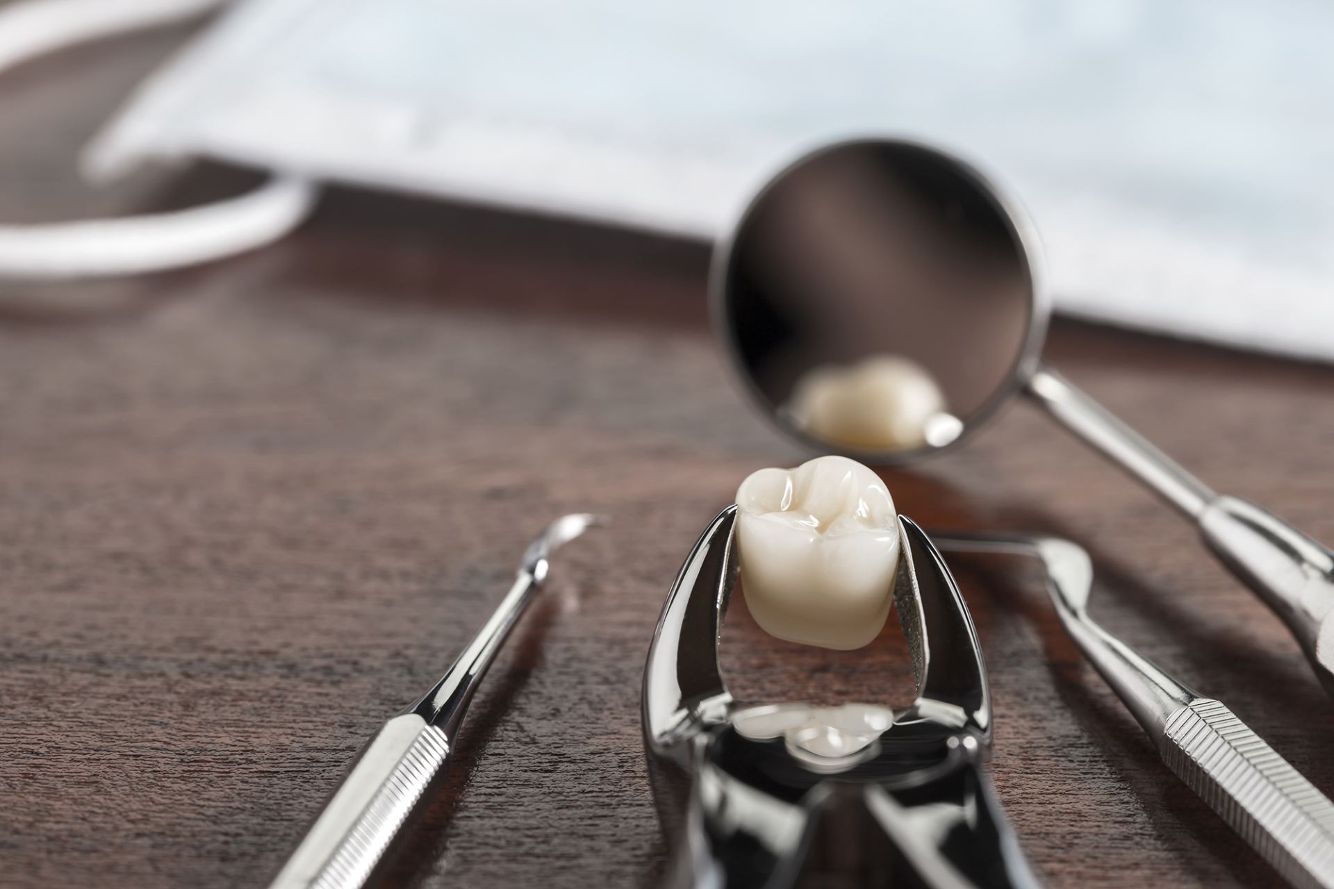 Strumenti odontoiatrici che circondano una corona dentale su un tavolo scuro