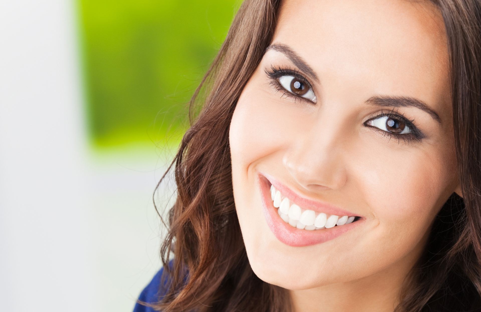 Donna sorridente con i capelli castani in un ritratto luminoso e ravvicinato.