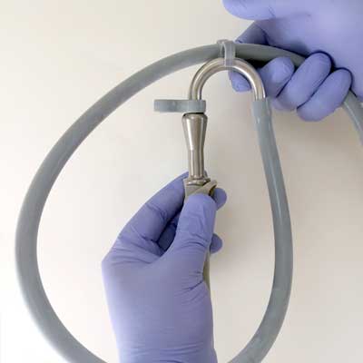 Hands in blue gloves connecting a stethoscope's tubing to its metal head.