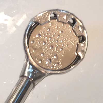 Close-up of a silver shower head with small water droplets on its surface.