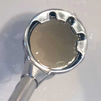 Close-up of a chrome-colored shower head with a unique notched design, likely in a bathroom setting.