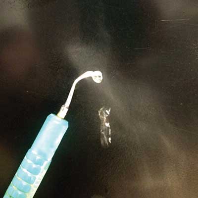 A surgical tool emitting a mist, possibly in an operating room setting.