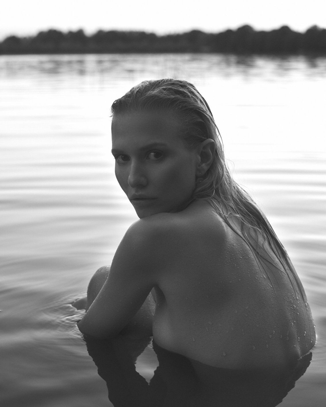 Frau im Wasser, Blick über die Schulter. Schwarzweiß, natürliches Licht.