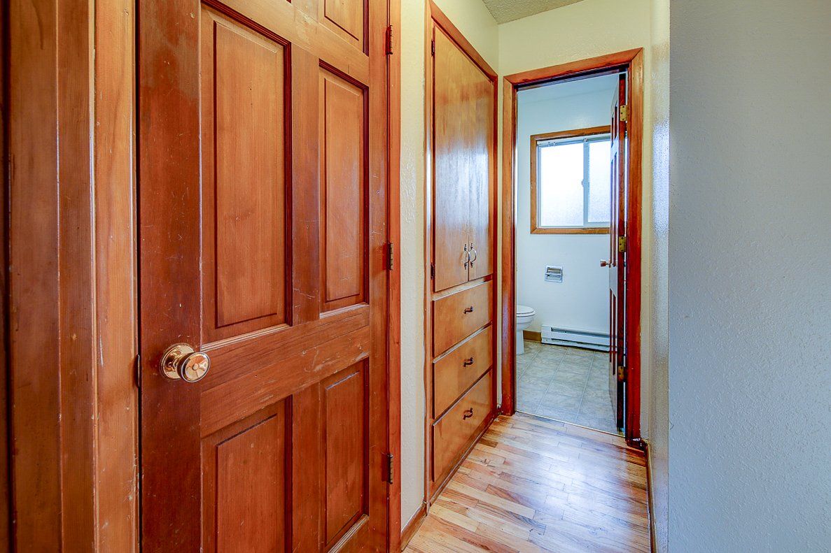 A hallway with wooden doors and drawers leading to a bathroom.