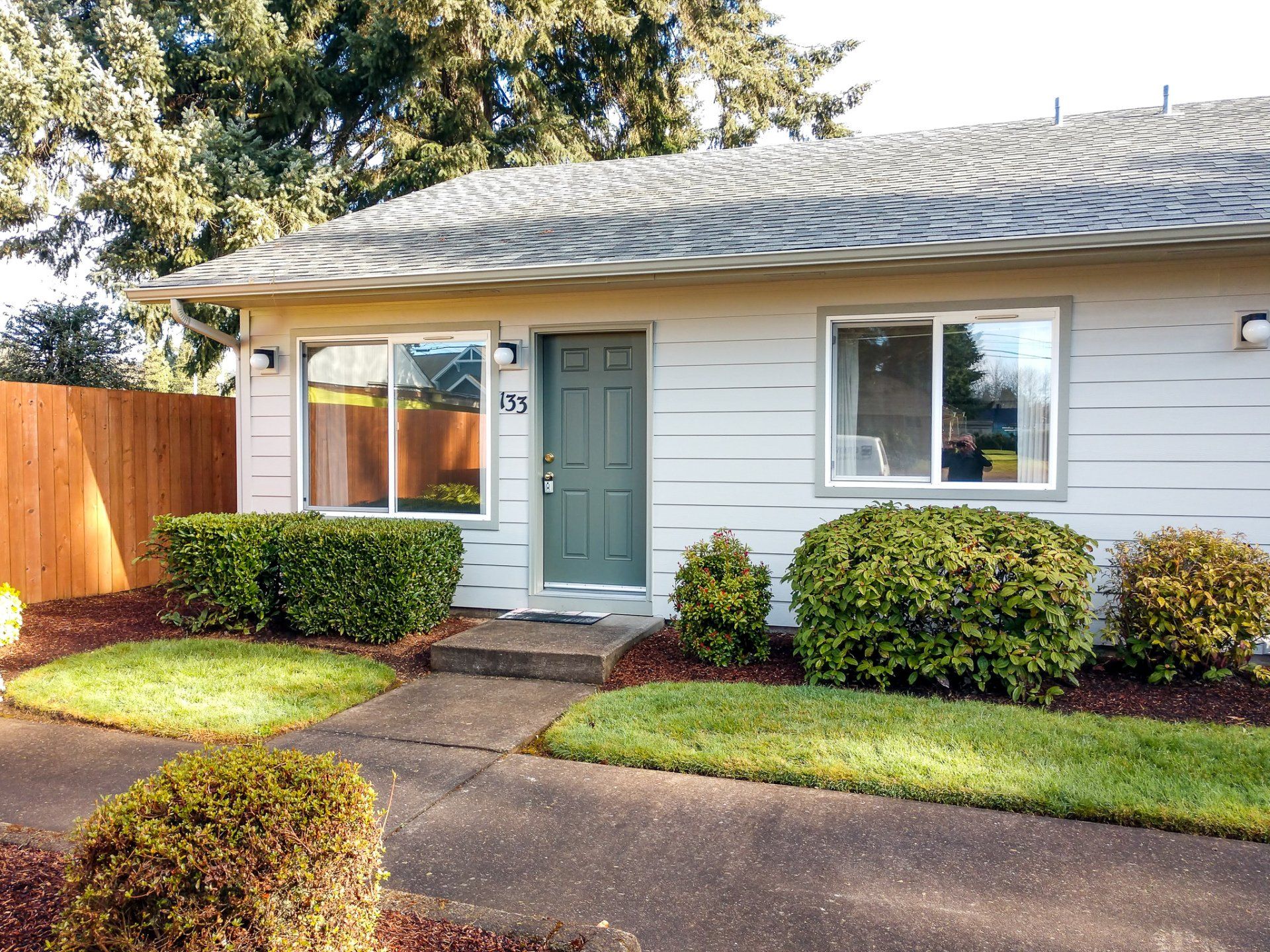 A small white house with a green door and a wooden fence