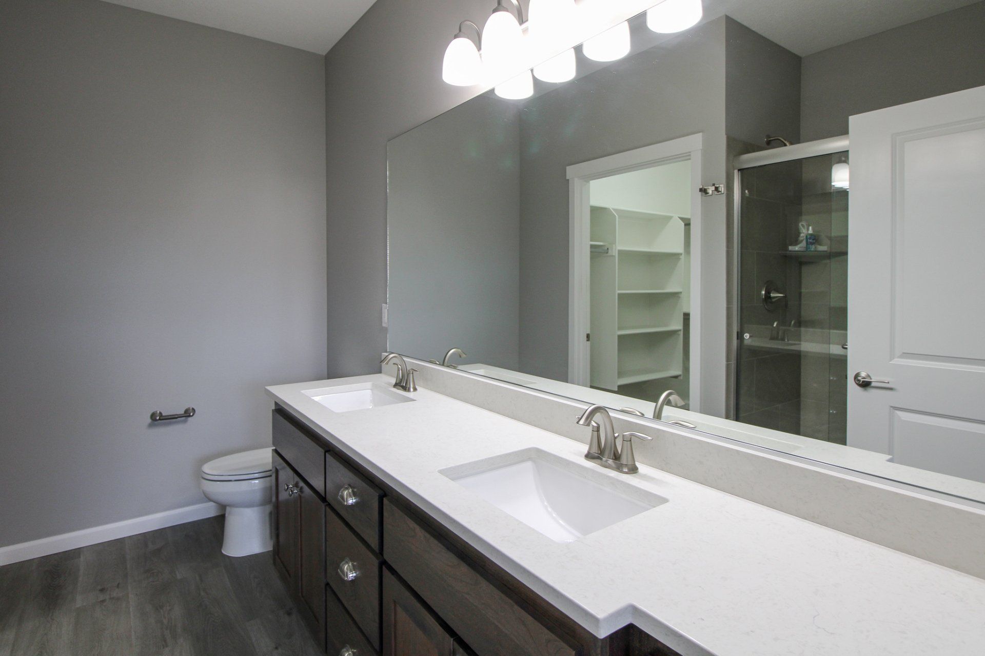 A bathroom with two sinks , a toilet , and a large mirror.