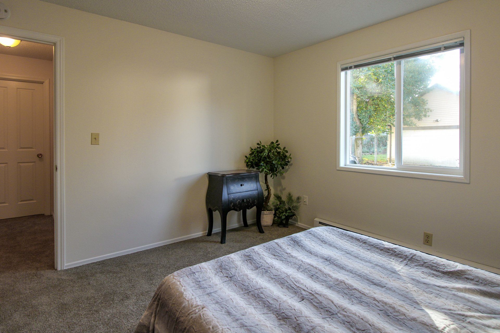 A bedroom with a bed , dresser , and window.