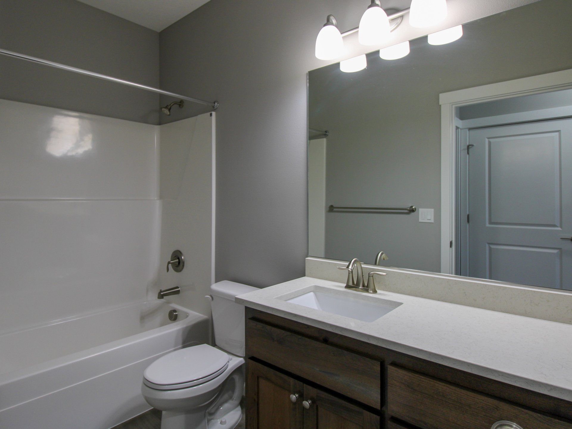 A bathroom with a toilet , sink , bathtub and mirror.