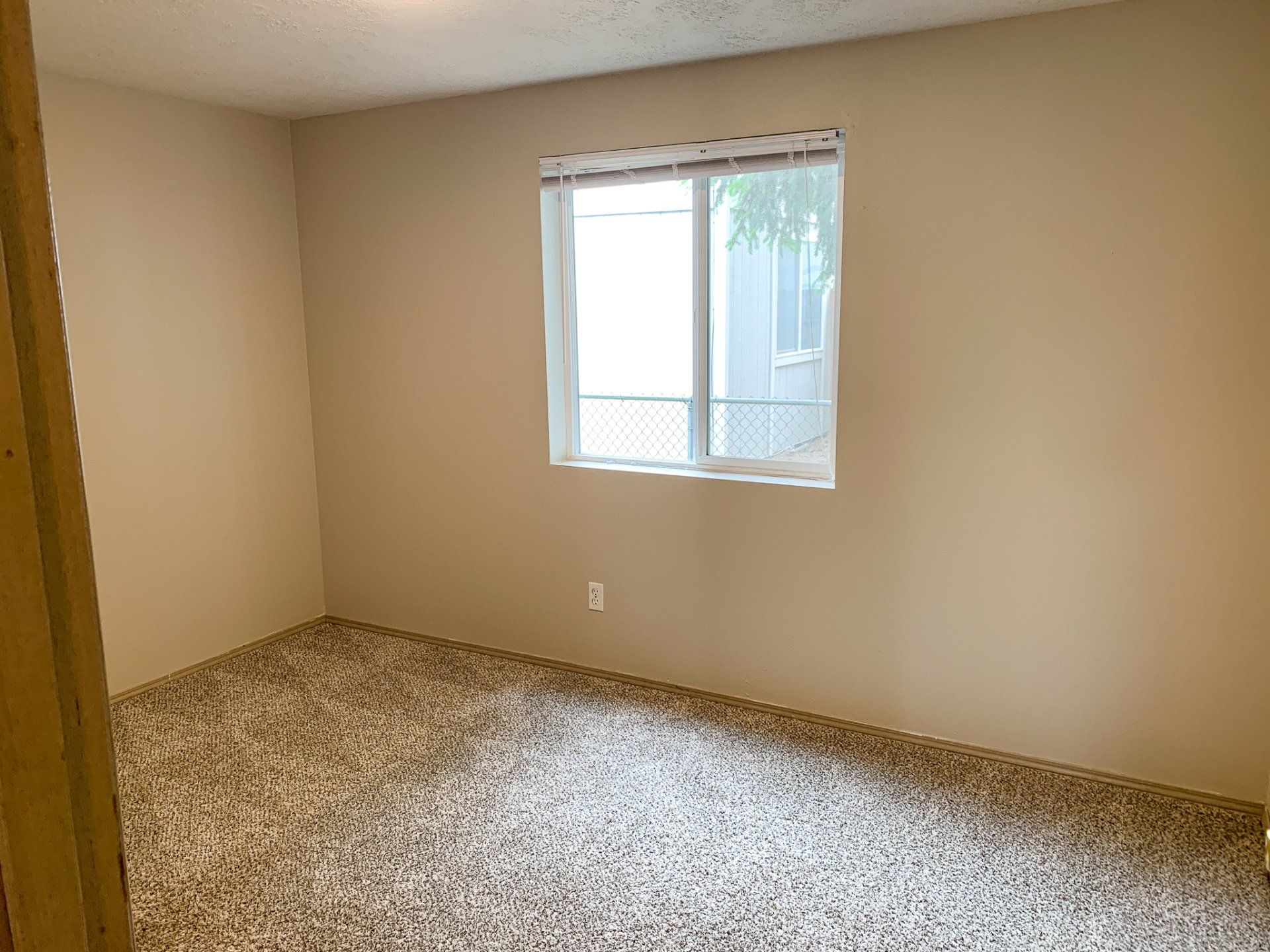 An empty bedroom with a sliding glass door and a window.