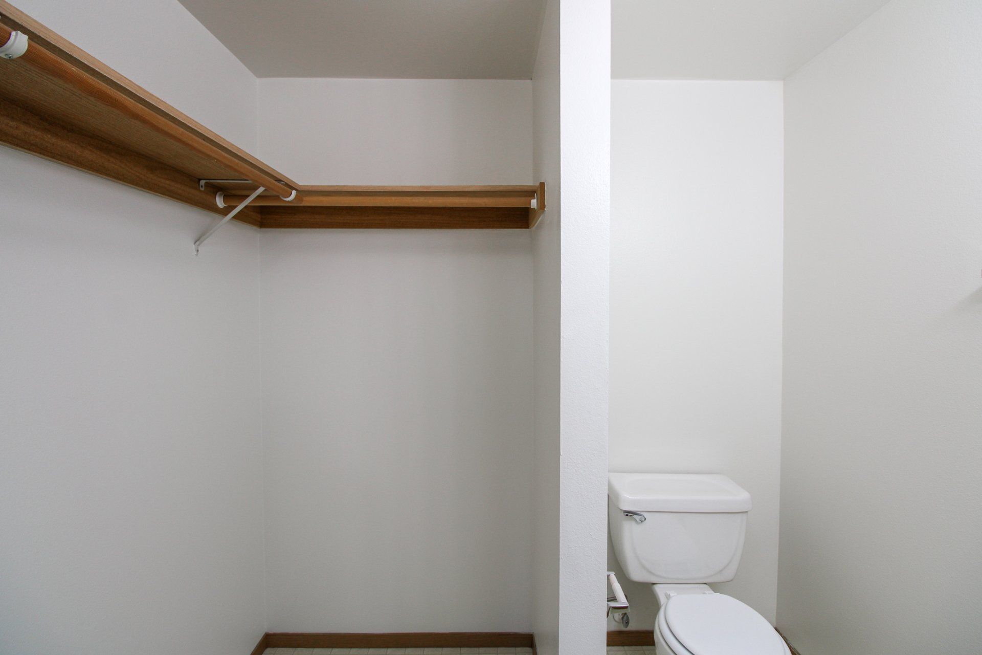 A bathroom with a toilet and a walk in closet.
