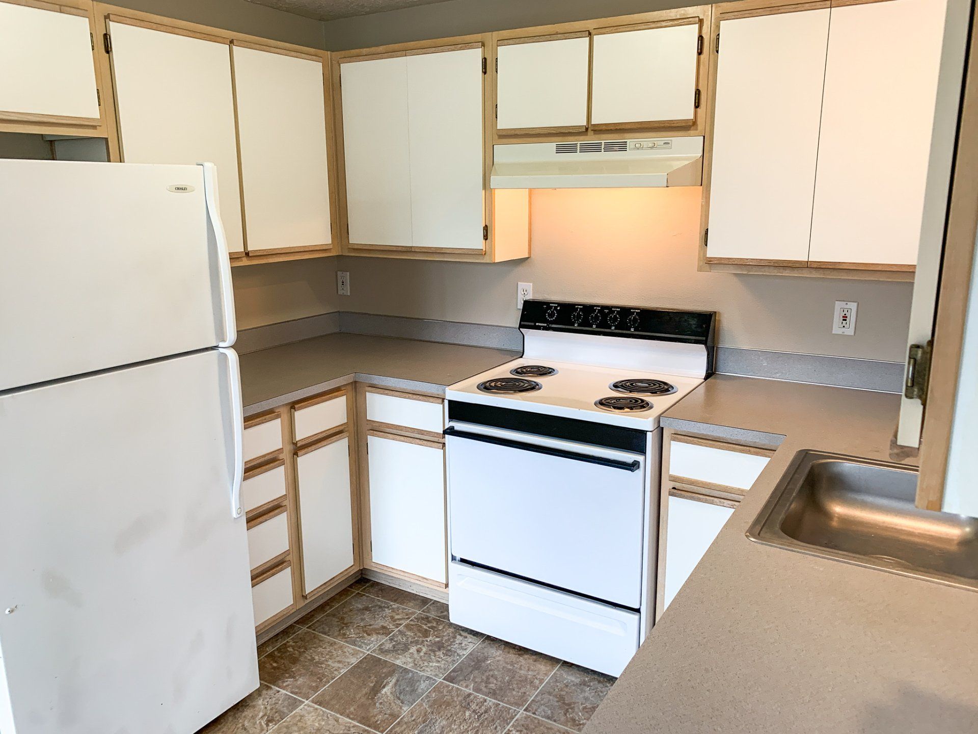 A kitchen with a stove , refrigerator and sink