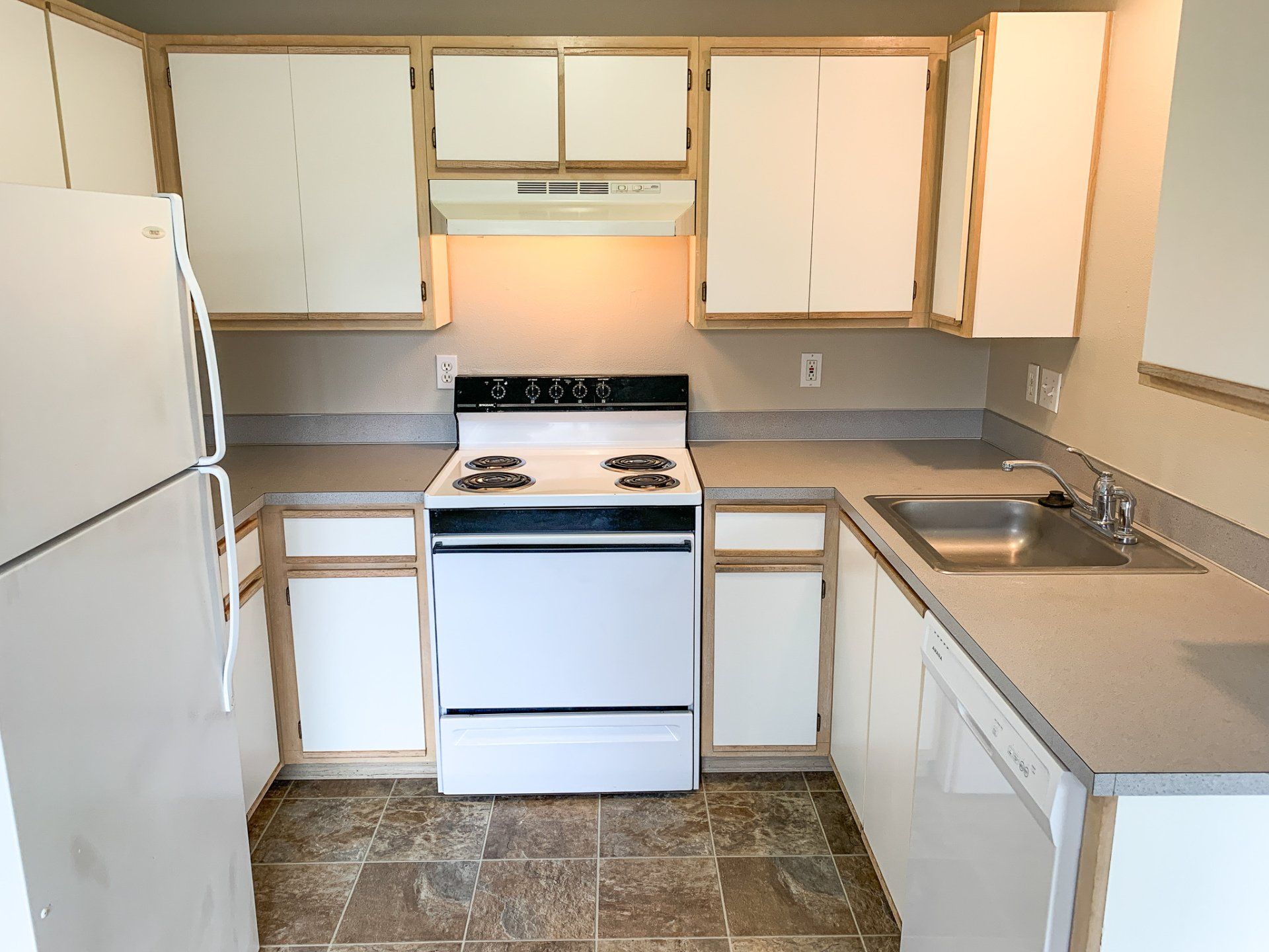 A kitchen with a stove a refrigerator and a sink