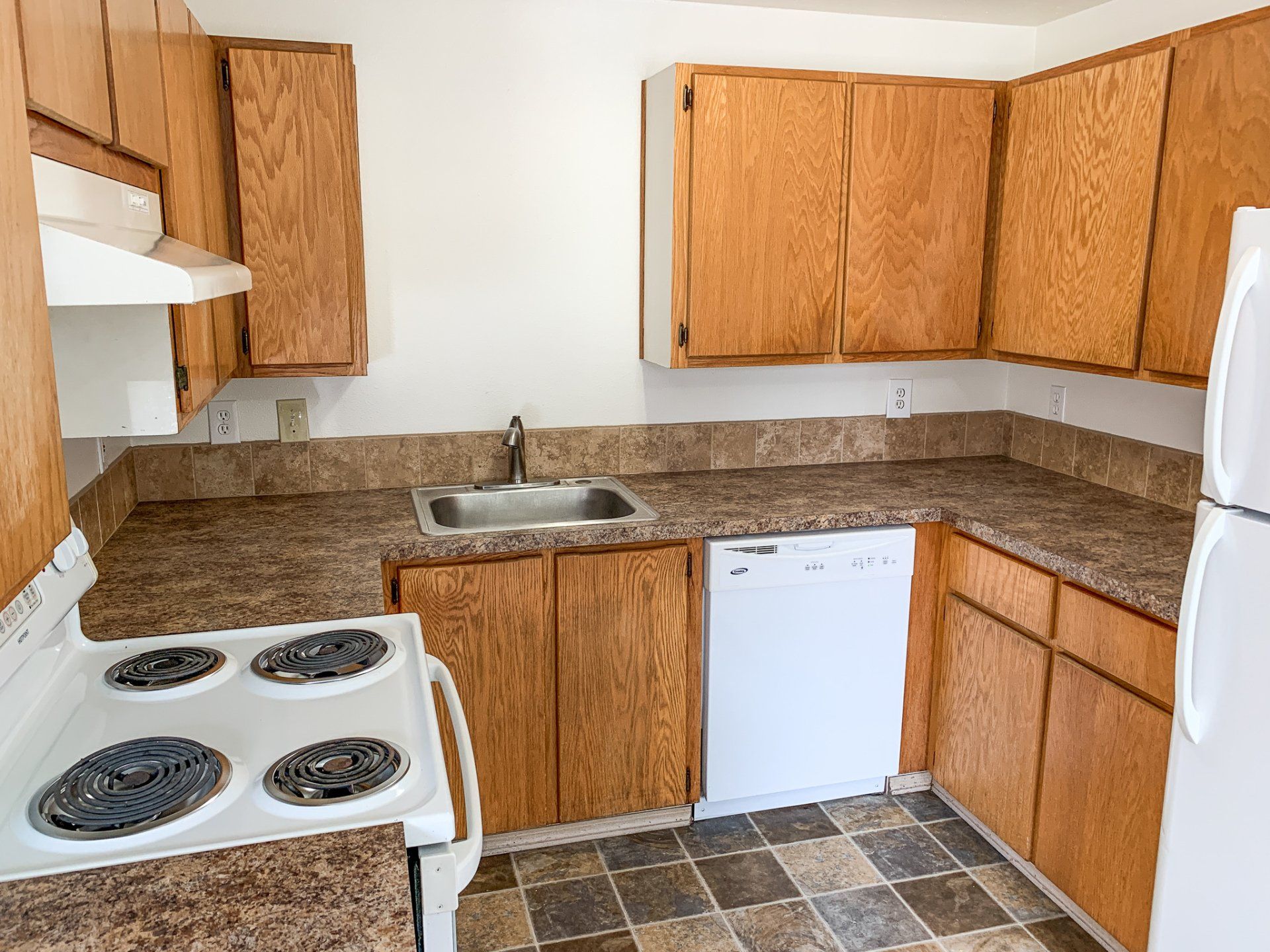 A kitchen with a stove , refrigerator , sink and dishwasher.