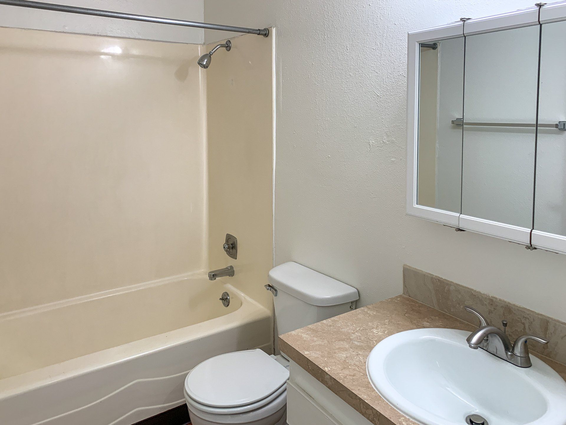 A bathroom with a tub , toilet , sink and mirror.