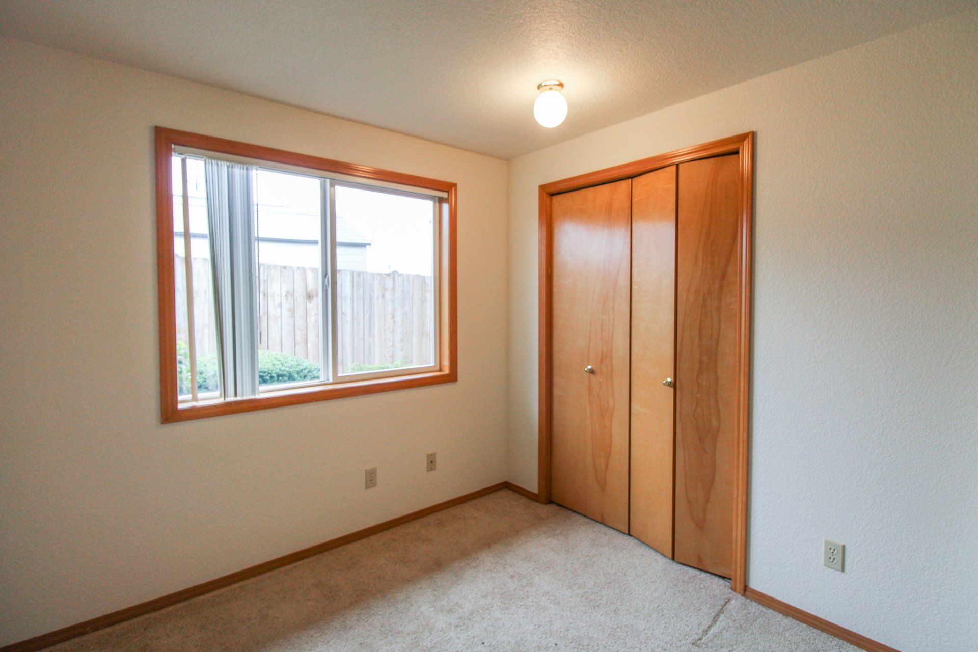 An empty bedroom with a large window and a closet.