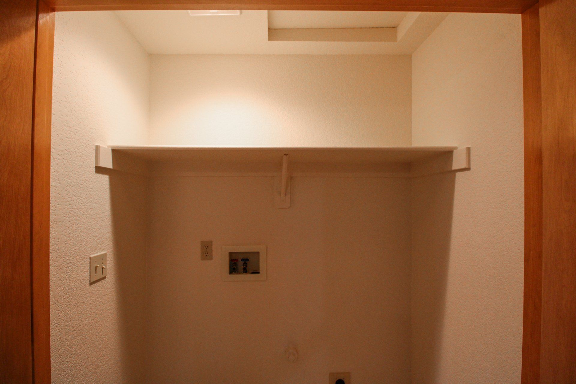 A closet with a shelf and hooks on the wall.