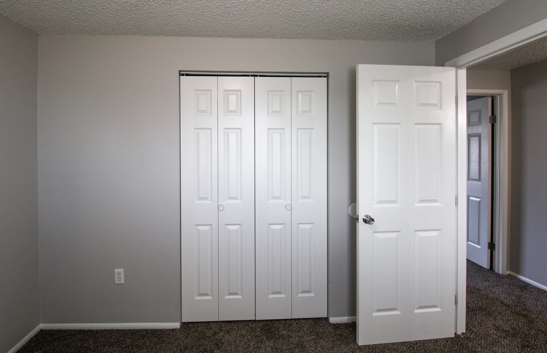 An empty bedroom with a closet and a door open.